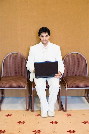 Portrait of a businessman sitting on a chair and using a laptop Stock Photo - Premium Royalty-Free, Code: 630-01873954
