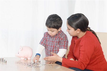 families wealthy - Boy making stacks of coins near a piggy bank with his mother sitting beside him Stock Photo - Premium Royalty-Free, Code: 630-02219241