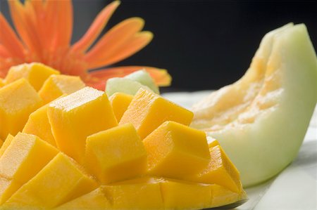 Close-up of mango slices and melon slices with a daisy flower Stock Photo - Premium Royalty-Free, Code: 630-02219480