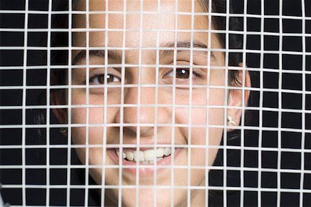 Portrait of a teenage girl hiding her face behind a net and smiling Stock Photo - Premium Royalty-Free, Code: 630-02219669