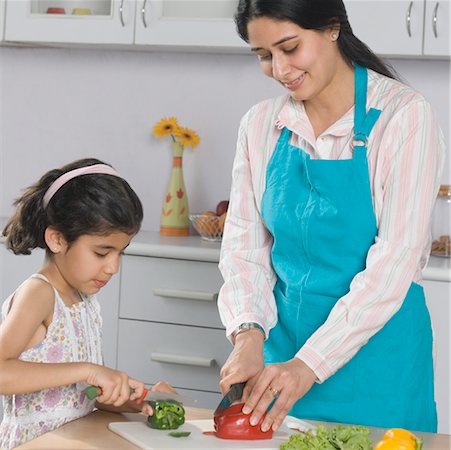 simsearch:630-02219943,k - Mid adult woman with her daughter cutting vegetables on a cutting board in the kitchen Stock Photo - Premium Royalty-Free, Code: 630-02220335