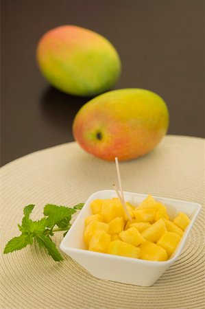 Close-up of a bowl of mango slices with mangoes and mint leaves Stock Photo - Premium Royalty-Free, Code: 630-02220648