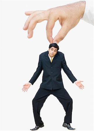domination - Person's hand pretending to hold a businessman Stock Photo - Premium Royalty-Free, Code: 630-02220665