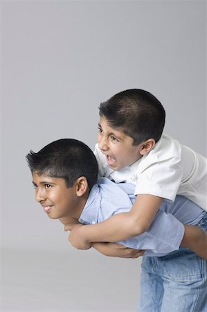 piggyback brothers - Side profile of a boy riding piggyback on another boy Stock Photo - Premium Royalty-Free, Code: 630-02220947