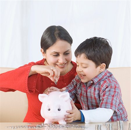 families wealthy - Jeune femme mettre une pièce de monnaie dans une tirelire avec son fils assis à côté de lui Photographie de stock - Premium Libres de Droits, Code: 630-02220971