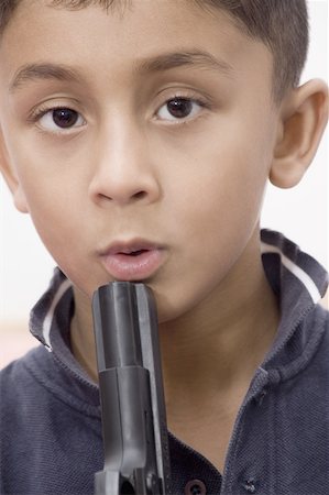 Portrait of a boy blowing in a gun barrel Stock Photo - Premium Royalty-Free, Code: 630-02221153