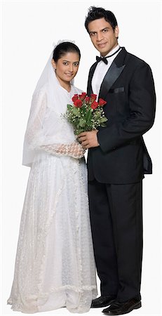 Portrait of a newlywed couple holding a bouquet of flowers and smiling Stock Photo - Premium Royalty-Free, Code: 630-03479490