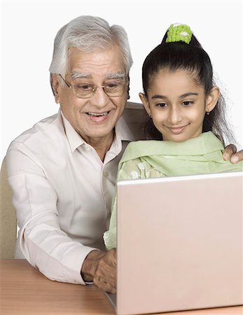 simsearch:630-03479740,k - Senior man using a laptop with his granddaughter and smiling Stock Photo - Premium Royalty-Free, Code: 630-03479604