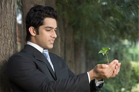 development suit business - Side profile of a businessman holding a plant Stock Photo - Premium Royalty-Free, Code: 630-03479837