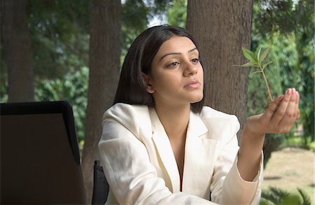 Businesswoman holding a plant and thinking Stock Photo - Premium Royalty-Free, Code: 630-03479857