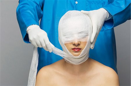 face front man - Surgeon wrapping bandage on woman's face Foto de stock - Sin royalties Premium, Código: 630-03480274
