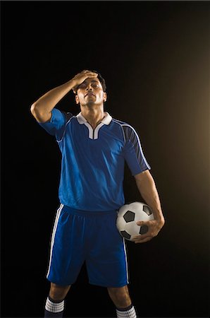 soccer player holding ball - Soccer player standing with his head in his hand Stock Photo - Premium Royalty-Free, Code: 630-03480335