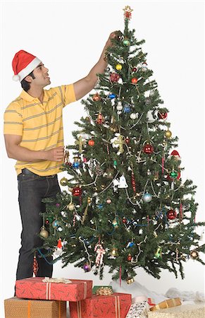 Man decorating a Christmas tree and smiling Stock Photo - Premium Royalty-Free, Code: 630-03480390