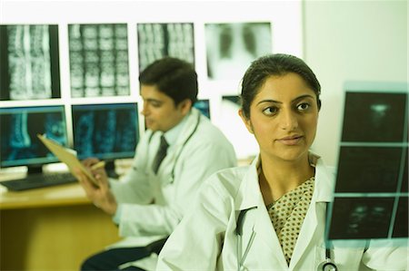 Female doctor examining X-Ray report and her colleague writing prescription Stock Photo - Premium Royalty-Free, Code: 630-03480949