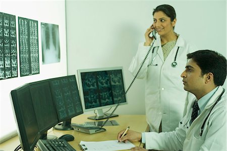 simsearch:630-03480875,k - Male doctor examining X-Ray report and his colleague talking on a phone Foto de stock - Sin royalties Premium, Código: 630-03480942