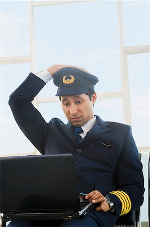 Pilot using a laptop at an airport and looking confused Stock Photo - Premium Royalty-Free, Code: 630-03481125