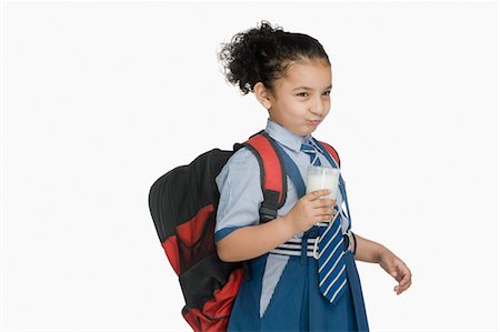 schoolbag - Schoolgirl holding a glass of milk and making a face Stock Photo - Premium Royalty-Free, Code: 630-03481154