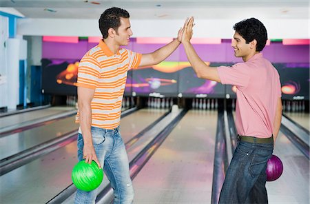 solid - Two young men giving high-five in a bowling alley Stock Photo - Premium Royalty-Free, Code: 630-03481564