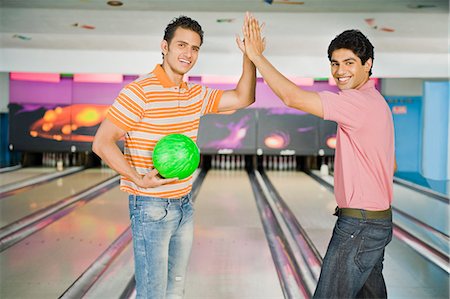 solid - Two young men giving high-five in a bowling alley Stock Photo - Premium Royalty-Free, Code: 630-03481562