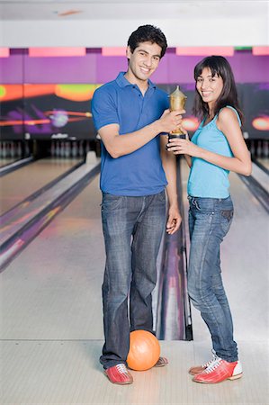 Young couple with a bowling ball and a trophy in a bowling alley Stock Photo - Premium Royalty-Free, Code: 630-03481616