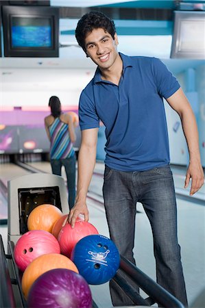 solid - Young man picking a bowling ball and a young woman bowling in a bowling alley Stock Photo - Premium Royalty-Free, Code: 630-03481646