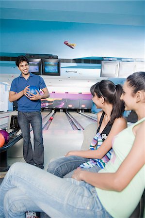 solid - Young man holding a bowling ball and looking at two young women Stock Photo - Premium Royalty-Free, Code: 630-03481666