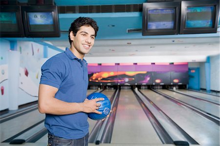 solid - Young man holding a bowling ball in a bowling alley Stock Photo - Premium Royalty-Free, Code: 630-03481679