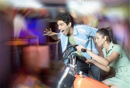 Young woman playing video game and a young man watching her game in a video arcade Stock Photo - Premium Royalty-Free, Code: 630-03481713