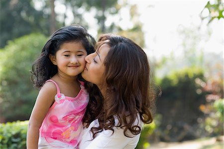 daughter kissing mother - Woman kissing her daughter in a park Stock Photo - Premium Royalty-Free, Code: 630-03483070