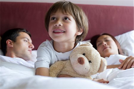 sleeping in - Boy sitting in parents' bed, hugging teddy bear Stock Photo - Premium Royalty-Free, Code: 632-05554063
