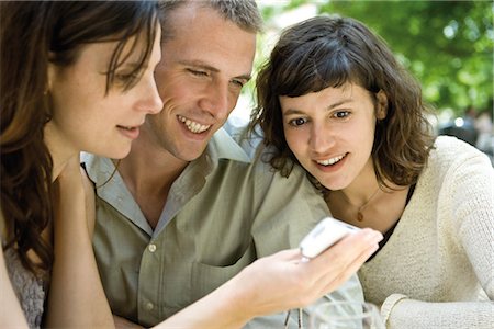 Friends looking at cell phone outdoors Stock Photo - Premium Royalty-Free, Code: 632-05554087