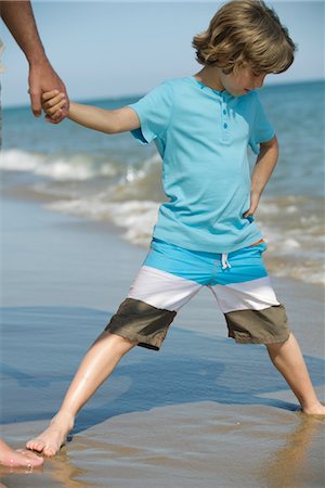 Boy standing with legs apart in wet sand at the beach Stock Photo - Premium Royalty-Free, Code: 632-05553543