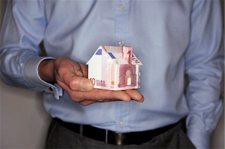 Man holding model house folded with euro banknote, mid section Stock Photo - Premium Royalty-Free, Code: 632-05553557