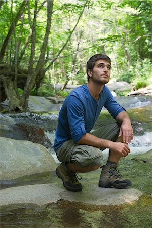Man crouching by stream in woods Stock Photo - Premium Royalty-Free, Code: 632-05553559