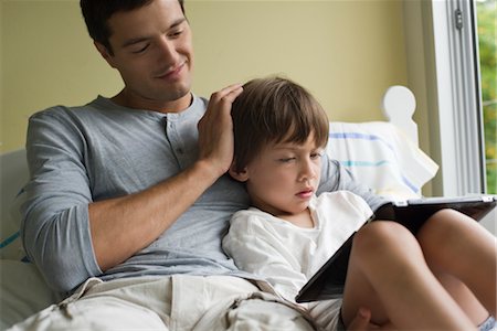 Father and son relaxing together with electronic book Stock Photo - Premium Royalty-Free, Code: 632-05553758