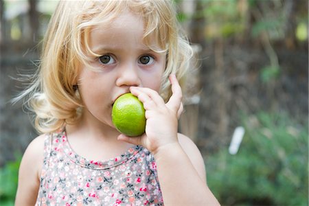 Little girl biting into lime Stock Photo - Premium Royalty-Free, Code: 632-05553788