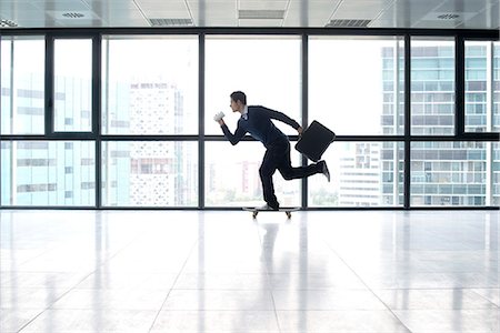 skateboarding - Businessman skateboarding with cup and briefcase in hands Stock Photo - Premium Royalty-Free, Code: 632-05604149