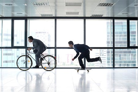 silhouette bike - One businessman riding bicycle, the other skateboarding Stock Photo - Premium Royalty-Free, Code: 632-05604283