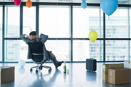 Businessman sitting in new office with balloons and boxes Stock Photo - Premium Royalty-Free, Code: 632-05604424