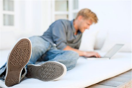 Man lying on bed using laptop computer Stock Photo - Premium Royalty-Free, Code: 632-05759455