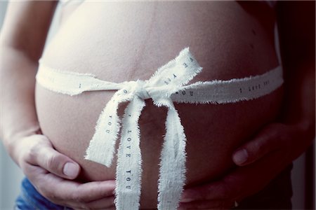 simsearch:632-05760692,k - Pregnant woman with ribbon wrapping around stomach, mid section Stock Photo - Premium Royalty-Free, Code: 632-05759687