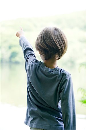 Boy looking at lake, pointing, rear view Stock Photo - Premium Royalty-Free, Code: 632-05759804