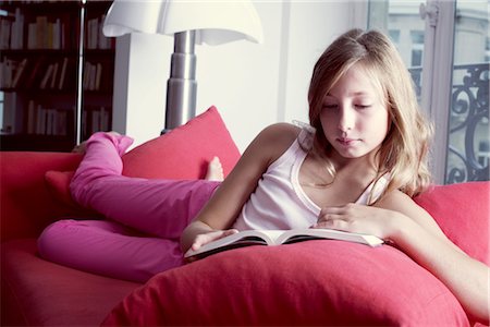 Girl reclining on couch reading book Stock Photo - Premium Royalty-Free, Code: 632-05759809