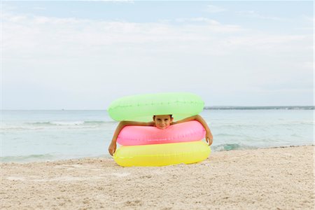 Girl playing with stack of inflatable rings on beach Stock Photo - Premium Royalty-Free, Code: 632-05759944