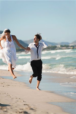 Bride and groom running hand and hand at the beach Stock Photo - Premium Royalty-Free, Code: 632-05759948