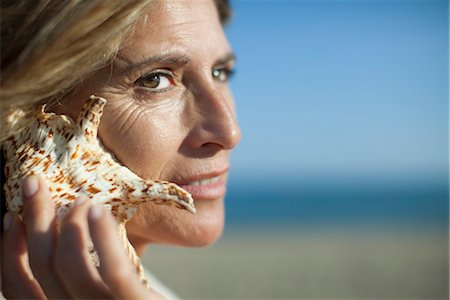 Woman listening to seashell Stock Photo - Premium Royalty-Free, Code: 632-05760513