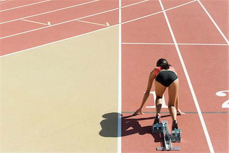 starter block - Woman crouched in starting position on running track, rear view Stock Photo - Premium Royalty-Free, Code: 632-05760718