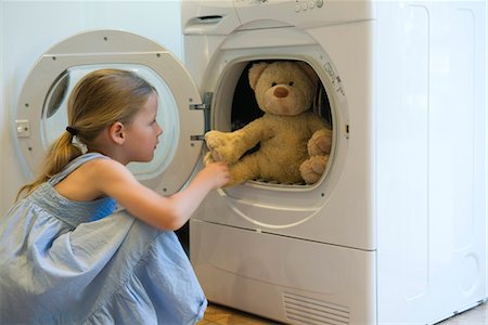 stuffed animal - Little girl taking teddy bear out of dryer Stock Photo - Premium Royalty-Free, Code: 632-05760808