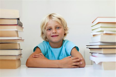 portrait of boy with arms crossed - Boy sitting between two stacks of books, portrait Stock Photo - Premium Royalty-Free, Code: 632-05816297
