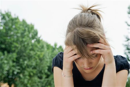 Upset young woman holding head and looking down Stock Photo - Premium Royalty-Free, Code: 632-05816611